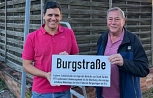 Alexander Fröhlich und Ortsvorsteher Karlfred Heidelbach präsentieren das neue Zusatzschild für die Burgstraße